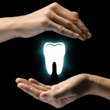 two hands protecting a glowing white tooth