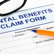 A dental benefits claim form with a pen