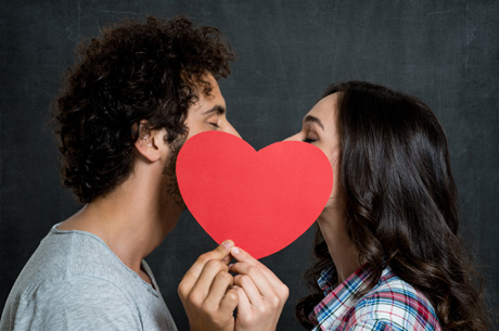Couple kissing behind a paper heart