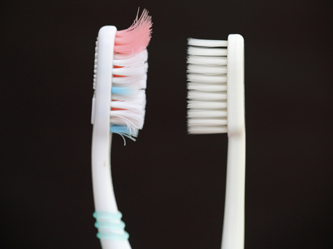 Toothbrush that needs replacing next to a new toothbrush