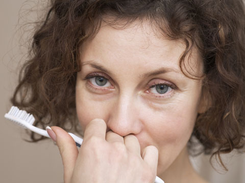 Woman hiding her smile holding a toothbrush