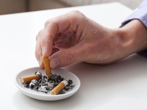 Man puts cigarette out in ashtray